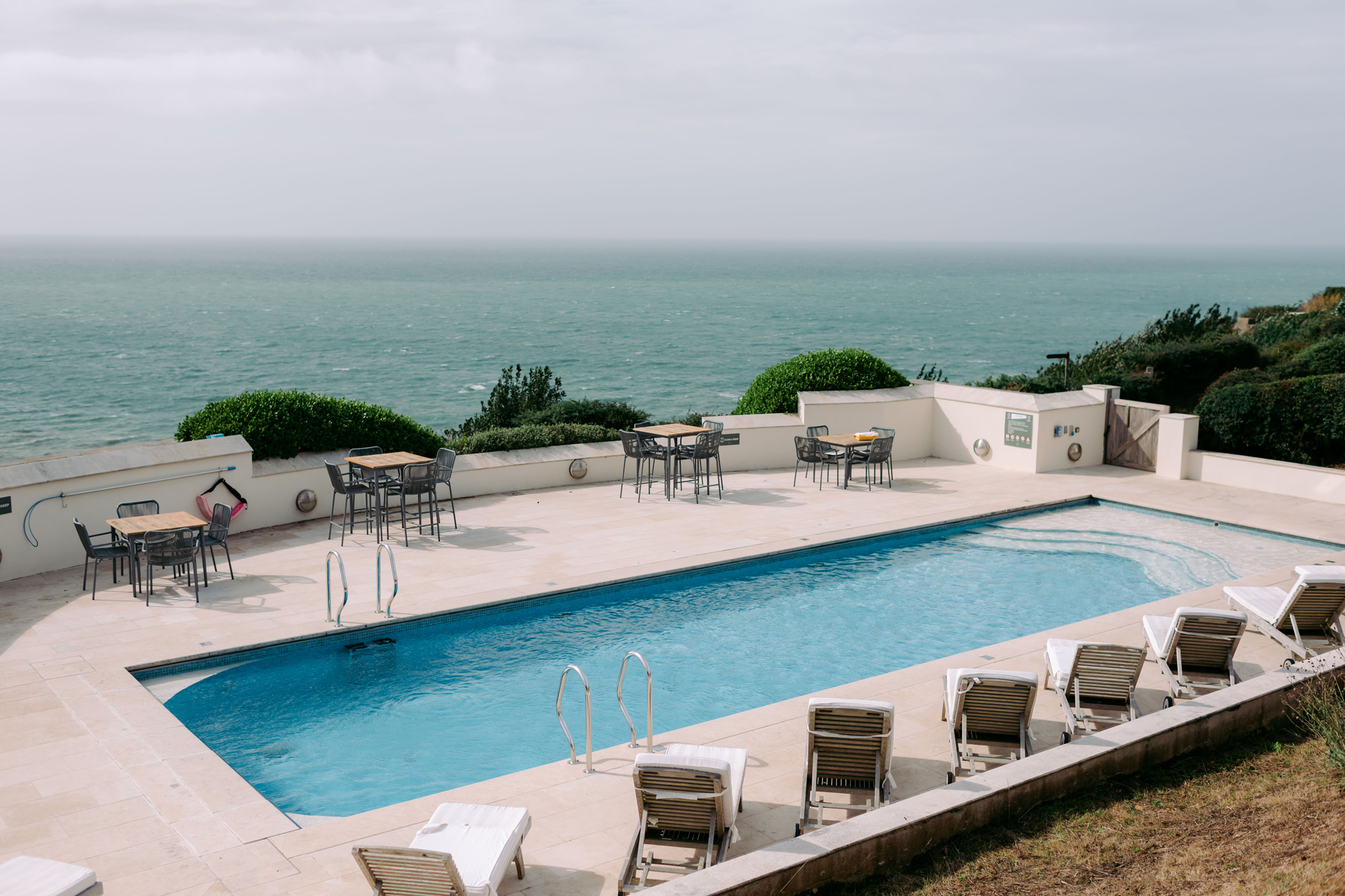 Outside pool with sunbeds surrounding and views of the South Devon coastline