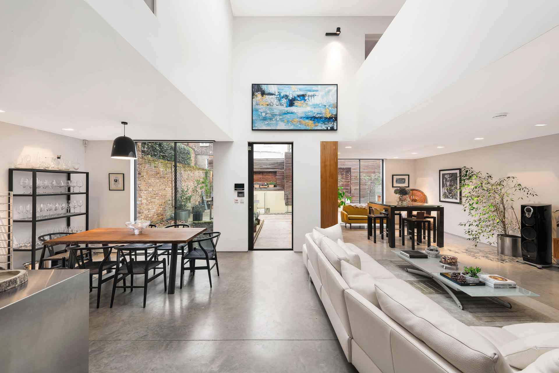 Modern dining/reception area with beige sofa and wooden dining table with black dining chairs.