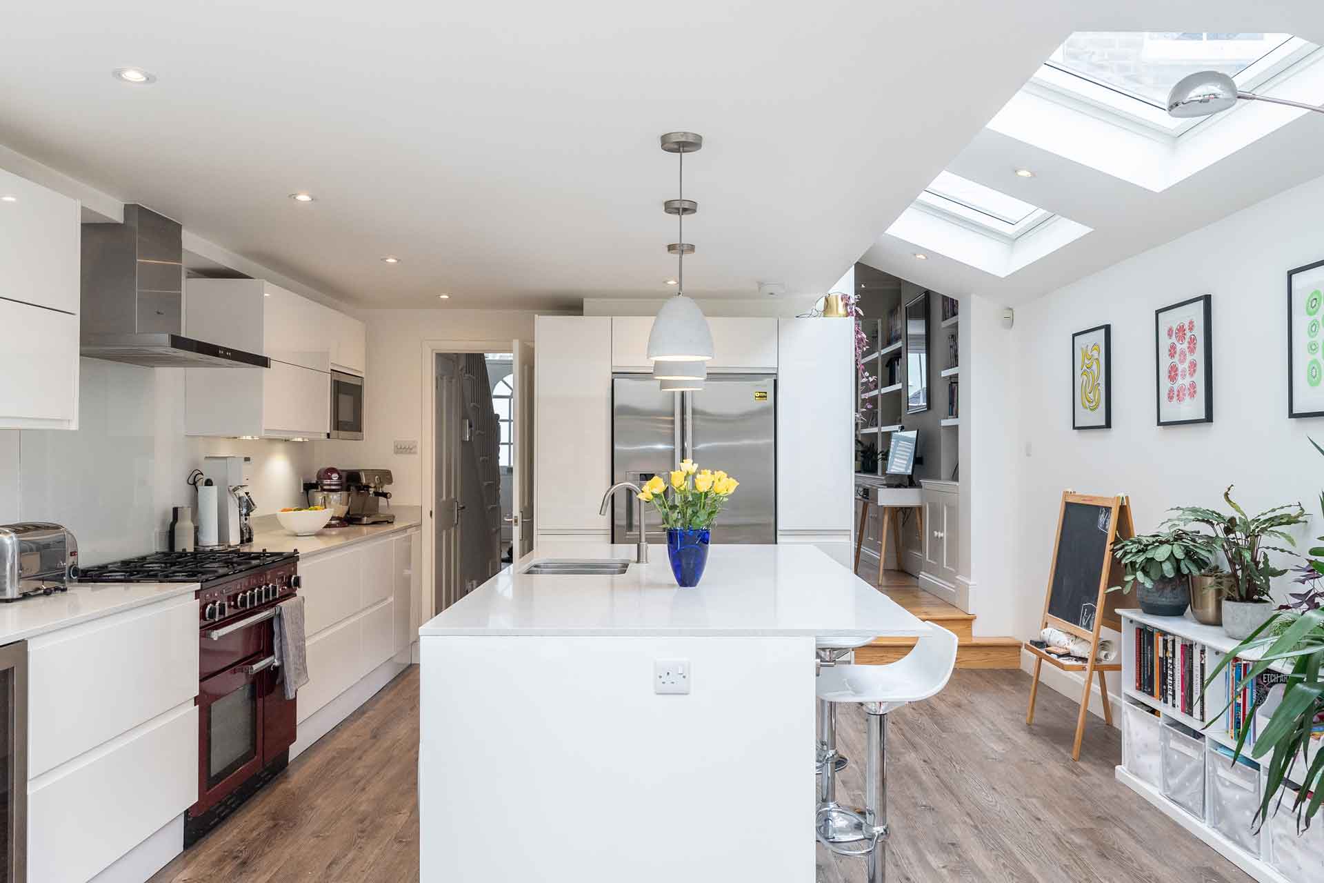 Large modern kitchen with white marble worktops and wooden floors.