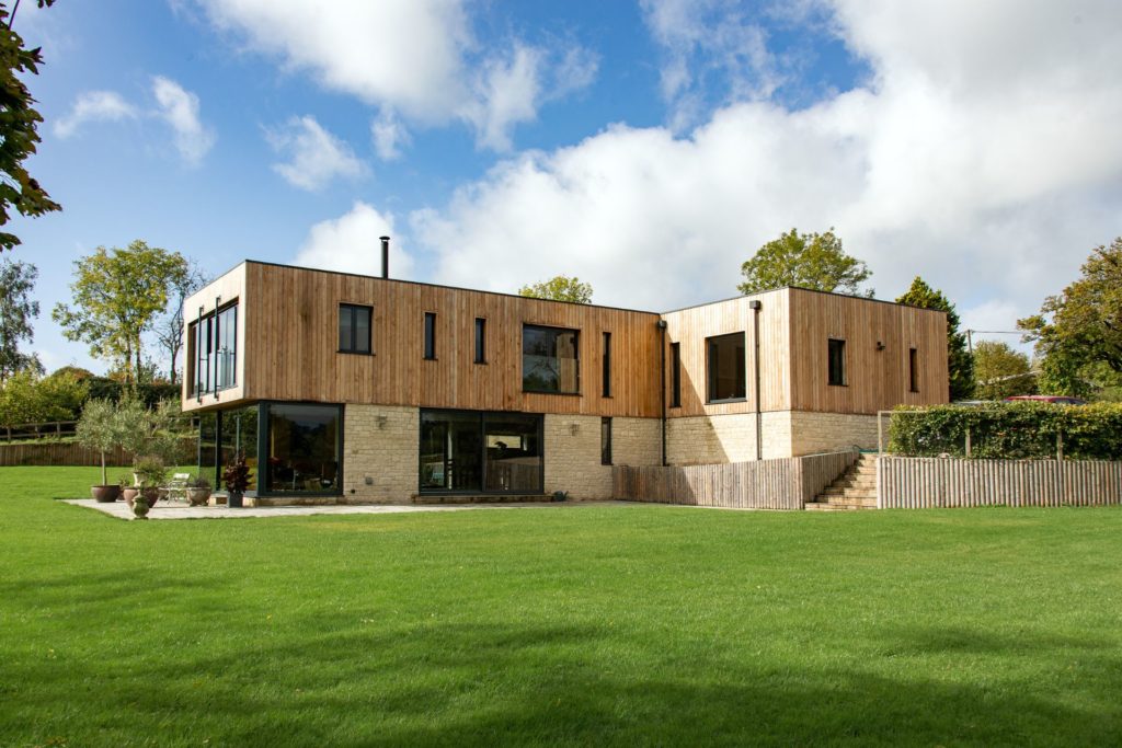 Wood-panelled contemporary home with lawns surrounding it.