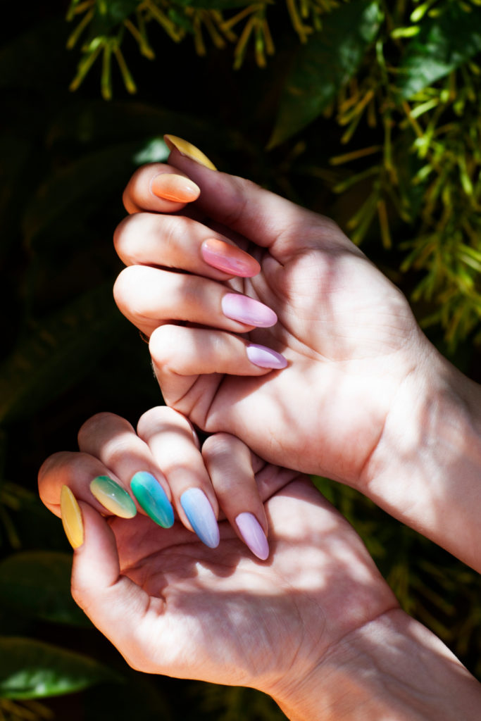 Close up of hands with rainbow nail designs