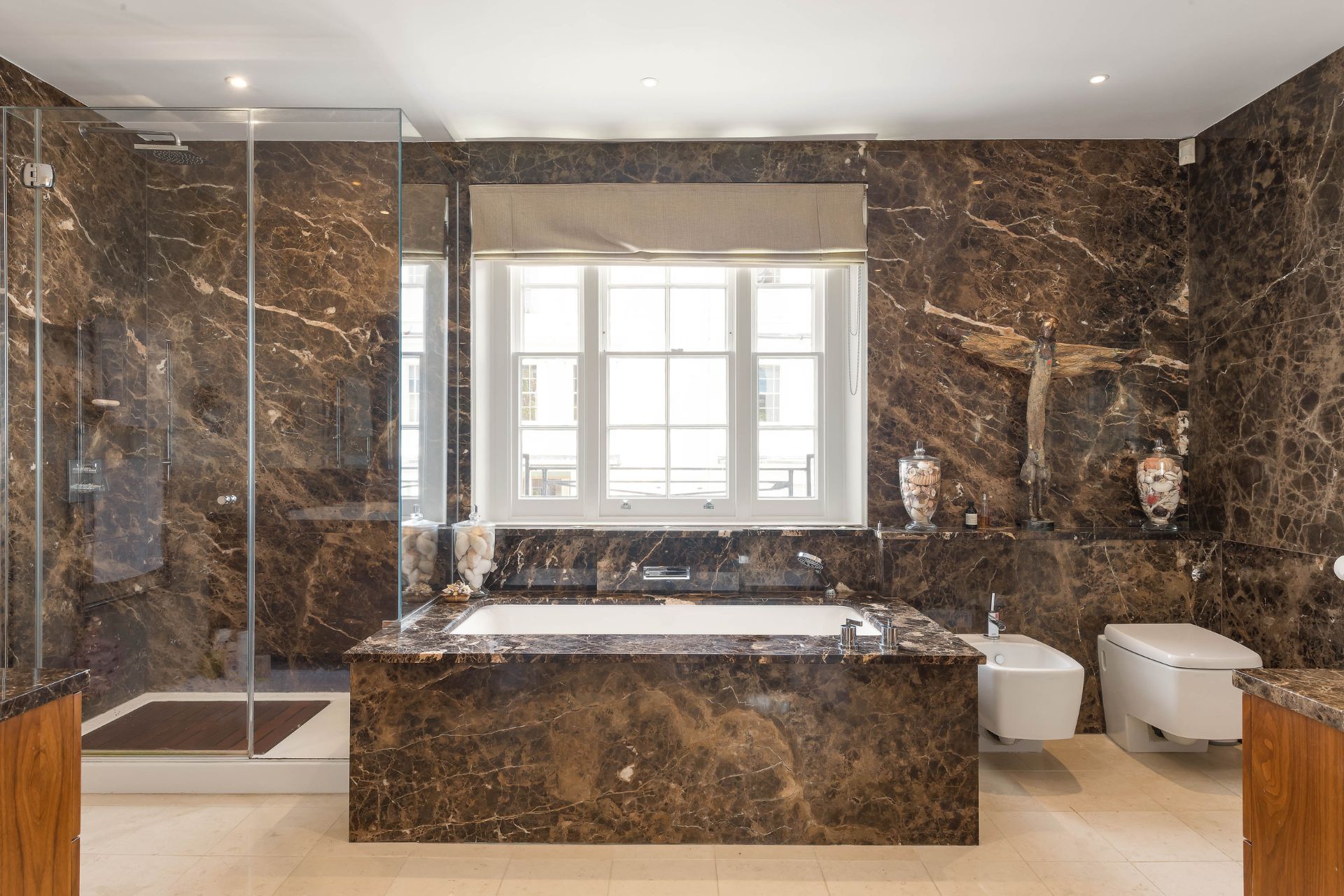 Bathroom with brown marble walls and a matching bathtub.