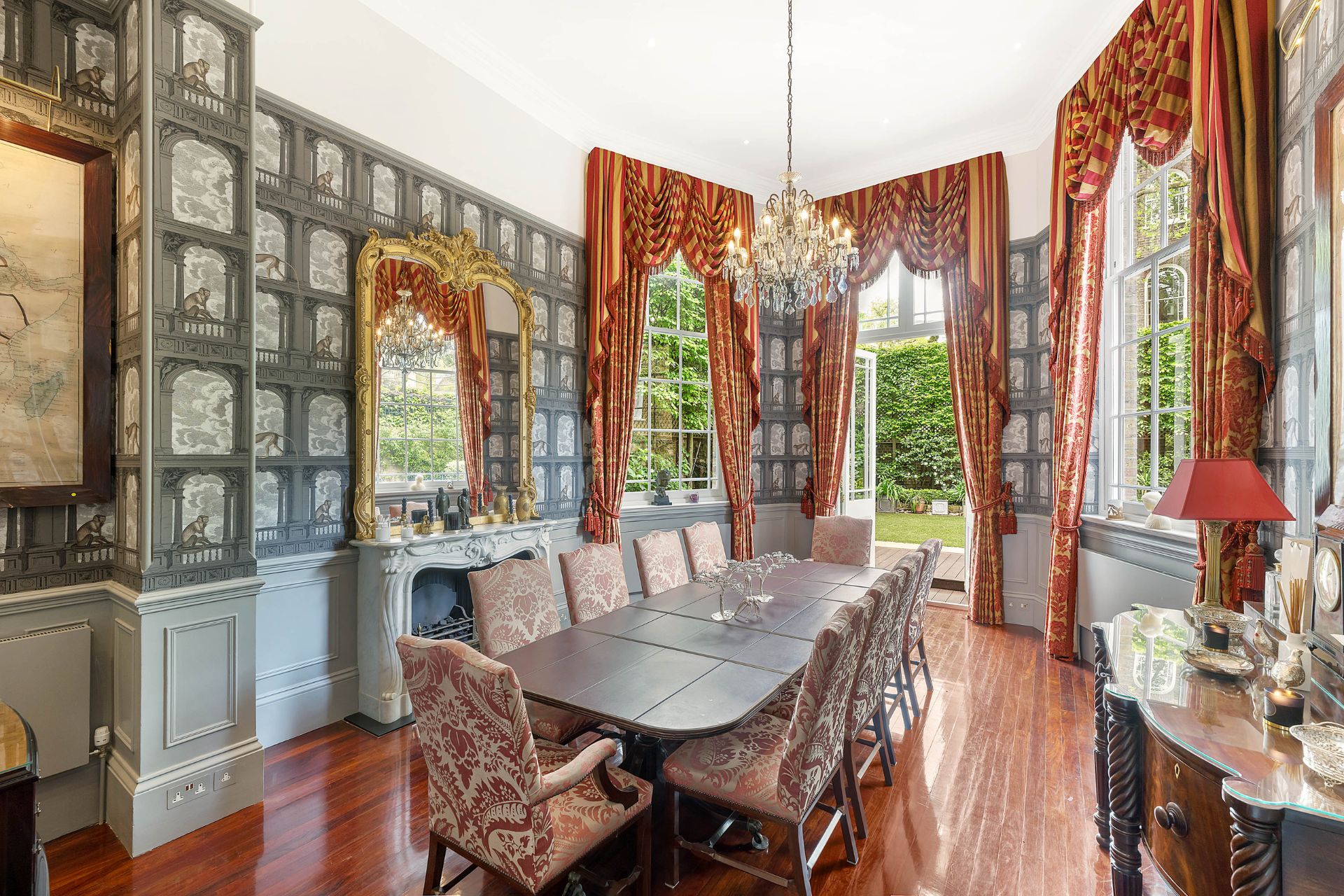 Dining room with wooden table, red drapes and a chandelier.