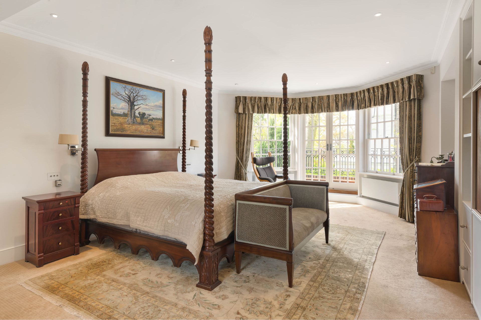 Bedroom with four poster bed, a yellow rug and wooden cabinets.