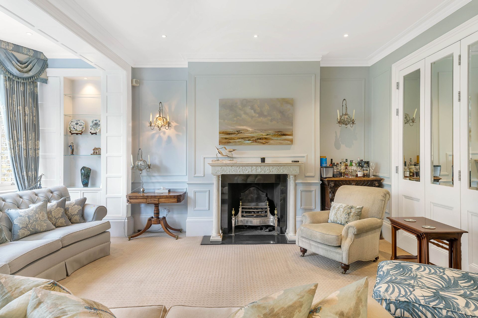 Living room with pale blue walls, cream sofas and a fireplace.