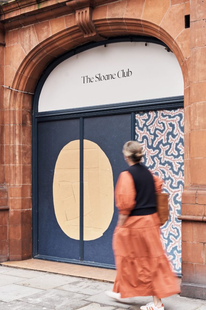 Exterior of The Sloane Club, with navy blue doors with an abstract print