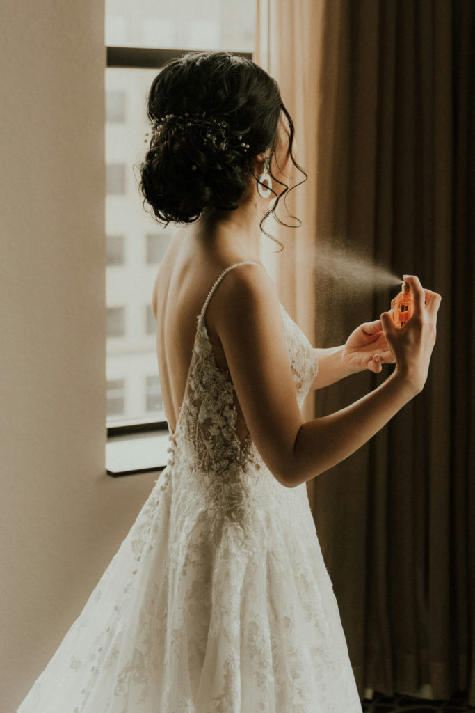 Woman in wedding dress spraying fragrance