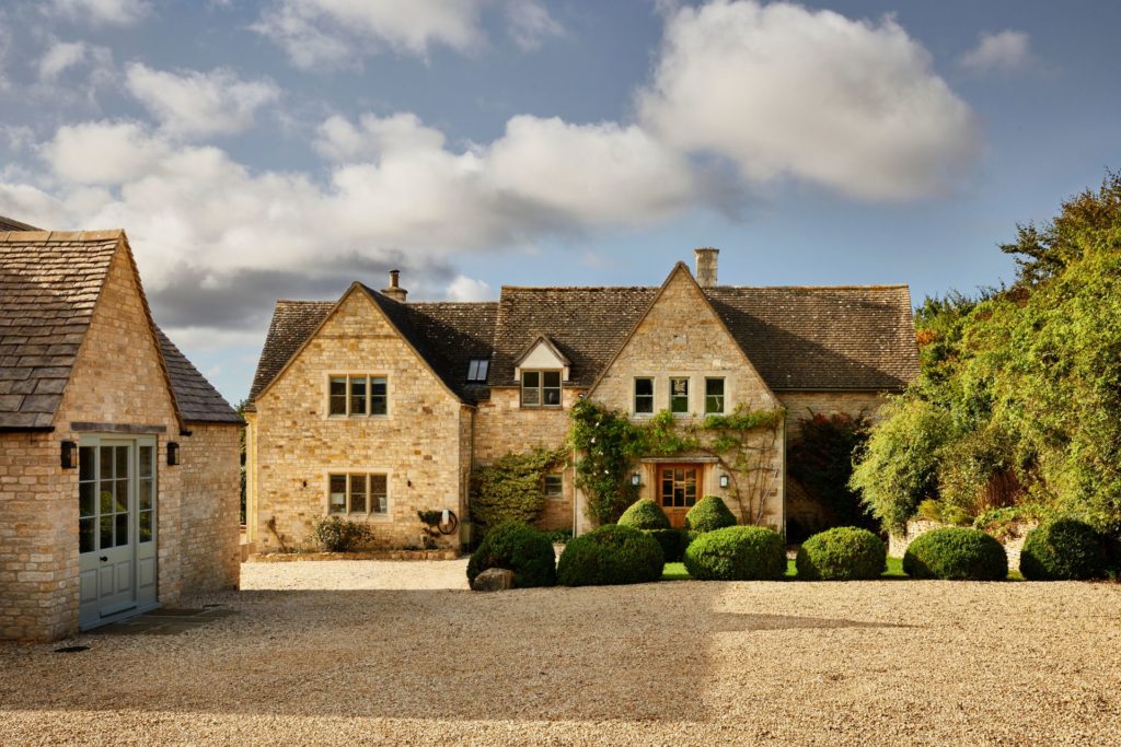 Cotswolds house with stone outbuildings and a gravel driveway.