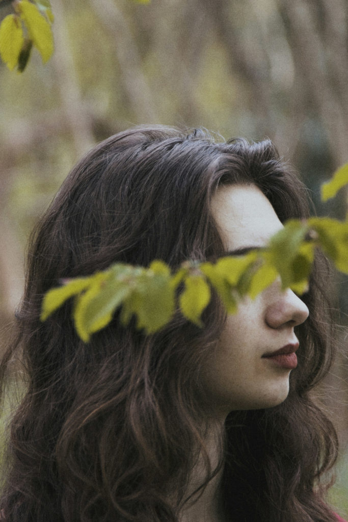 Woman with leaves covering face