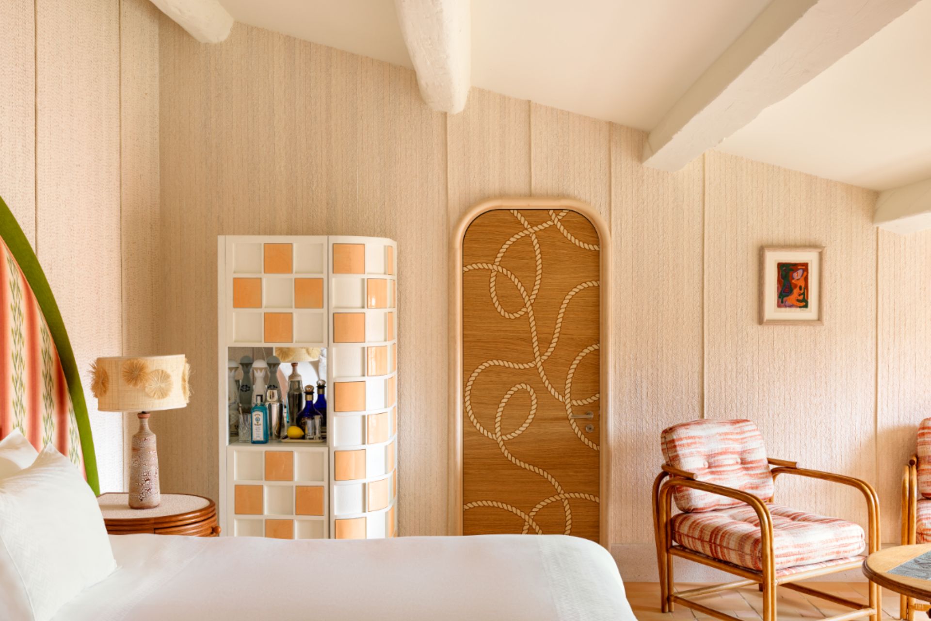 Hotel suite with orange and white checkered dresser, white bed linen and rattan headboard