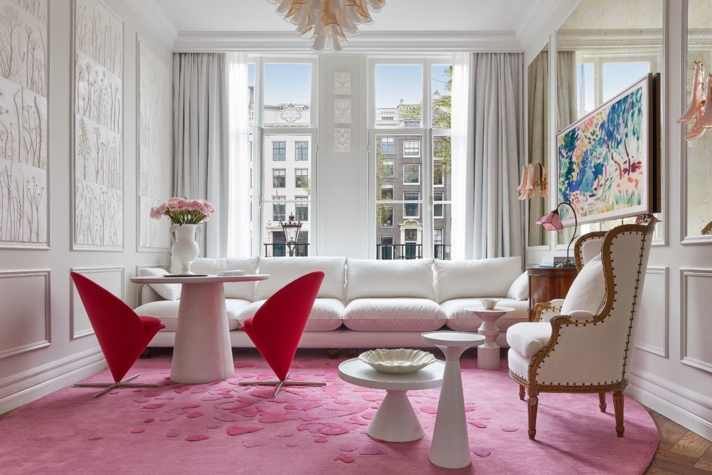 Hotel suite with blush pink carpet, red chairs and tulips