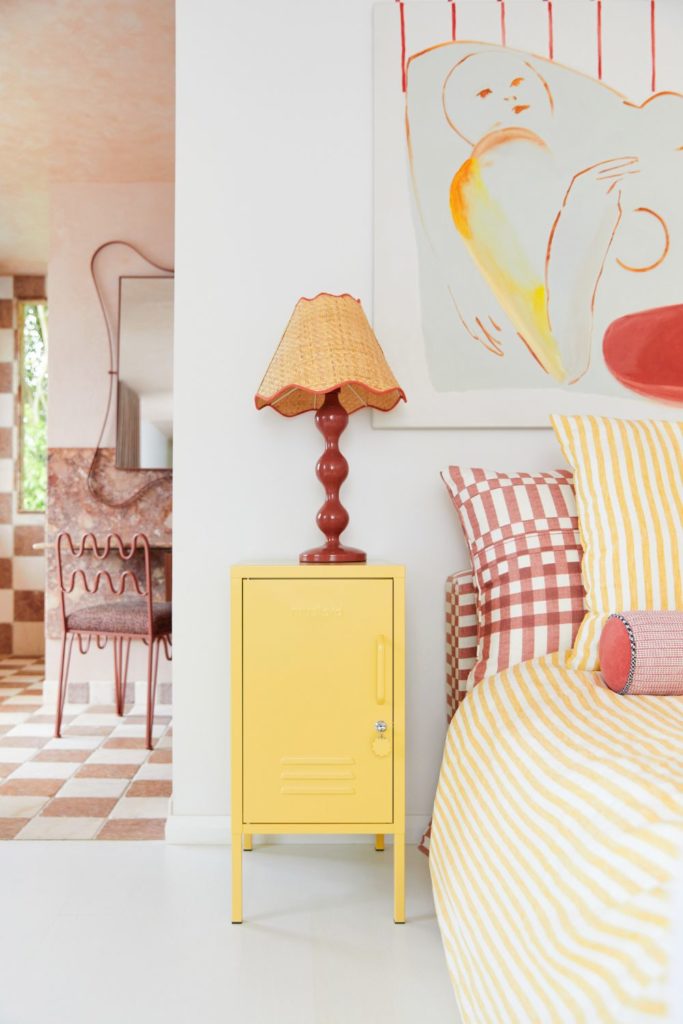 Bedroom with butter yellow bedside table, scalloped orange lamp and red and yellow gingham bedding