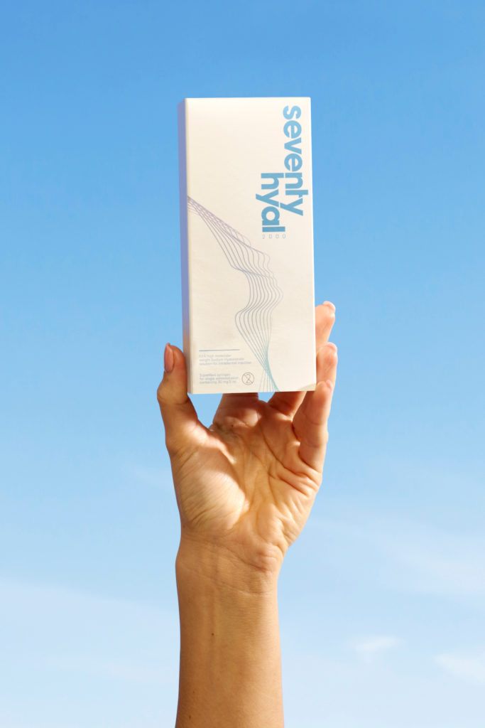 Hand holding white box in front of blue sky | Seventy Hyal 2000 hyaluronic acid for fitness