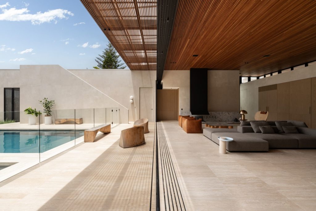 Living room with floor-to-ceiling doors opened up to a pool area