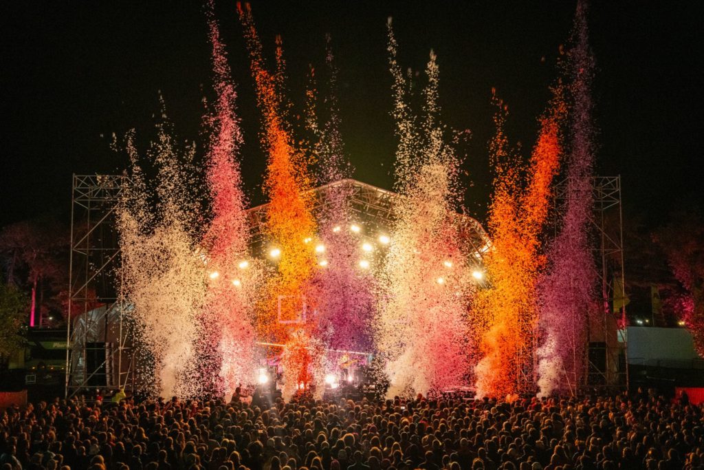 Orange and pink confetti cannons at outdoor festival stage