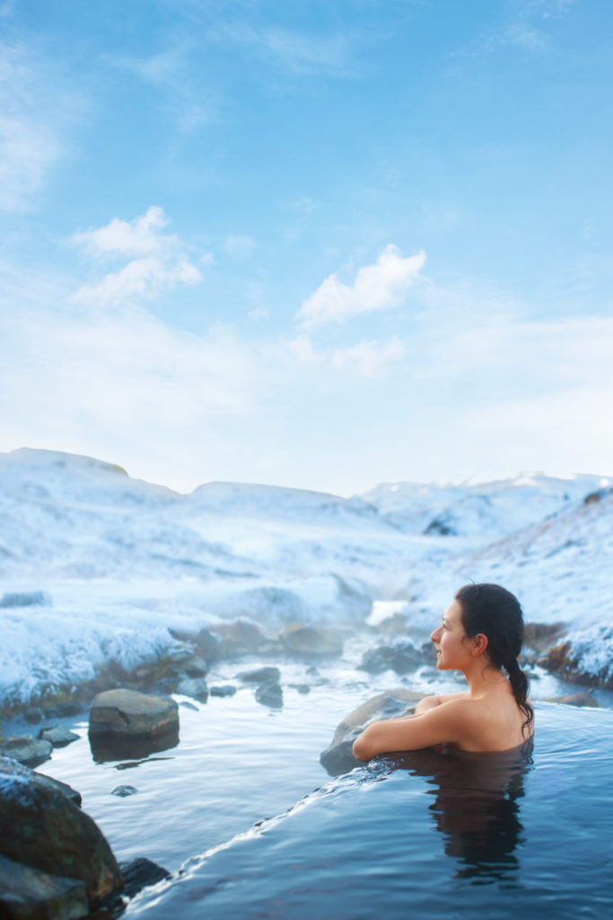 Woman in water surrounded by snowy mountains