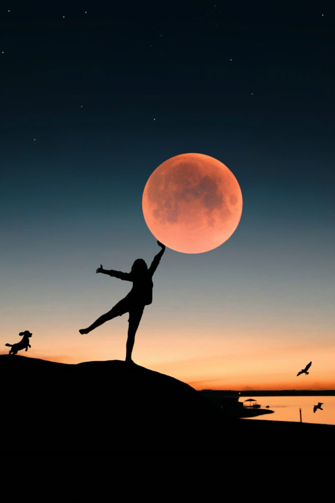 Silhouetted woman touching the moon