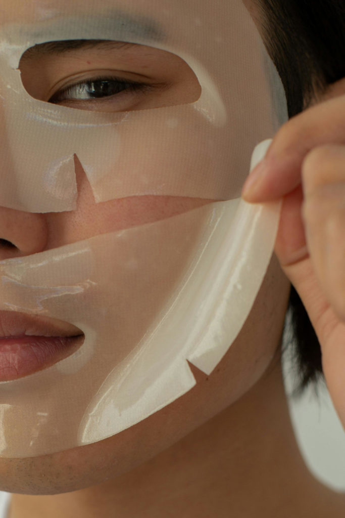 Close up of person's face, pulling off sheet mask for morning shed routine