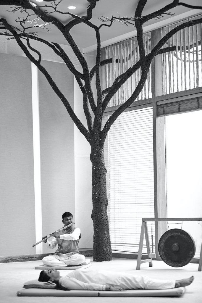 Man playing flute in yoga class at Six Senses Vana