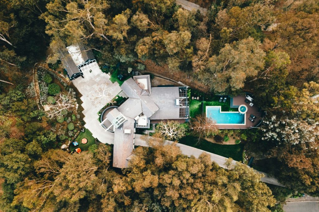 Aerial view of mansion with pool, surrounded by forest