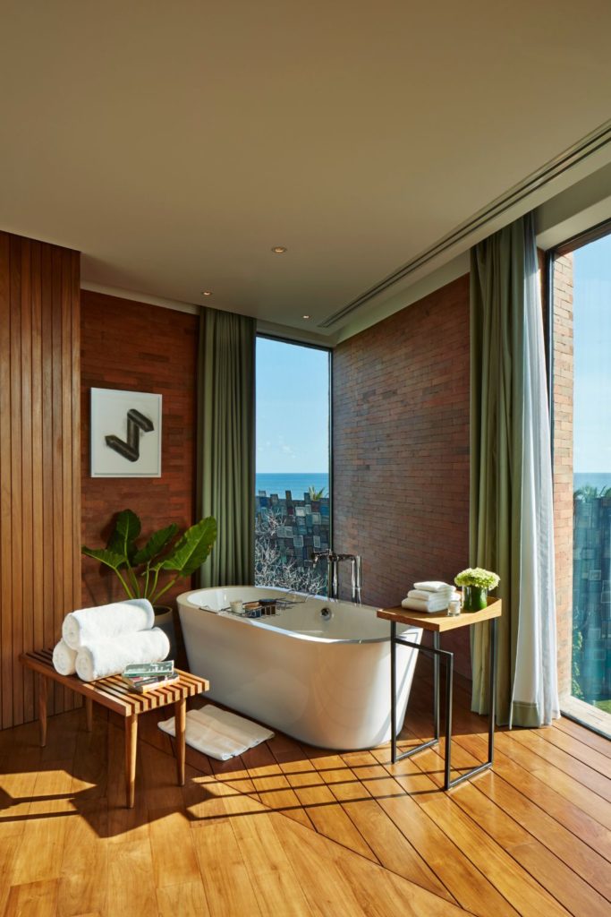 Balinese bathroom with freestanding bathtub and wooden towel rack