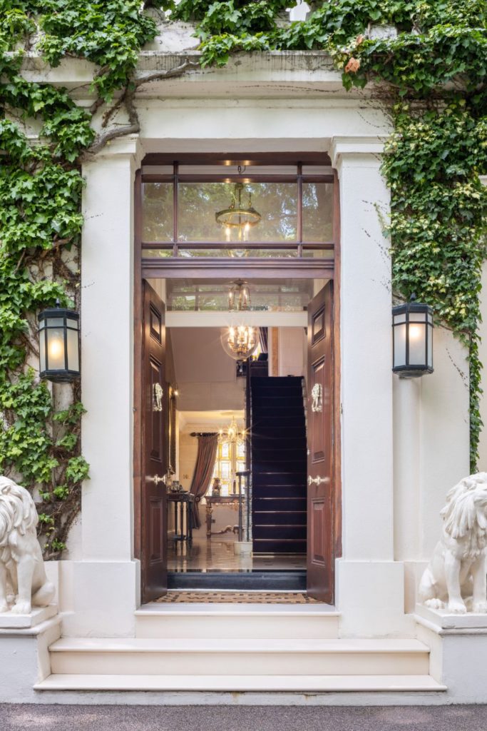 Mansion doorway with marble lion sculptures, Roman archway and an ivy-covered facade