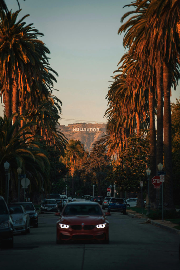 A car on a road in LA with Hollywood sign in the background