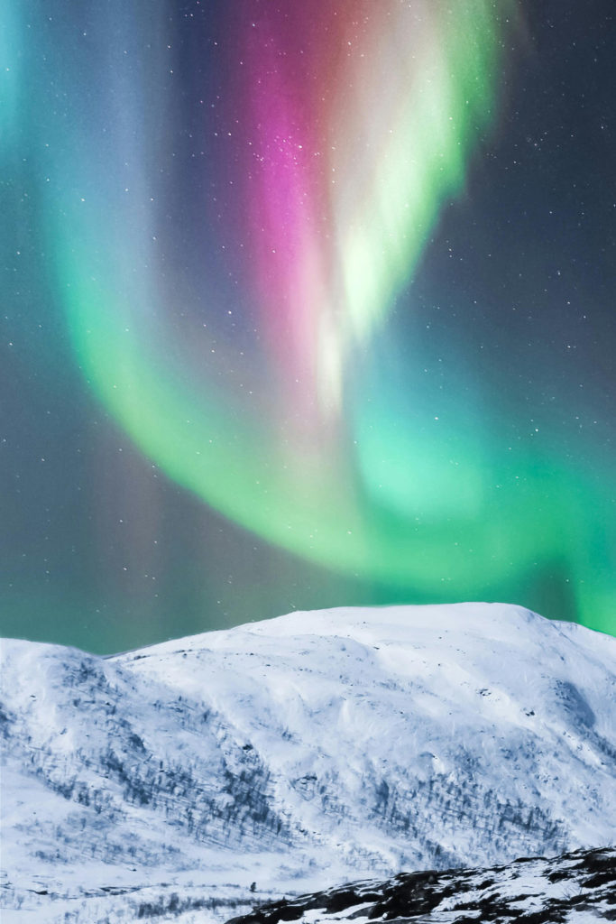 The Northern Lights over a snowy hill