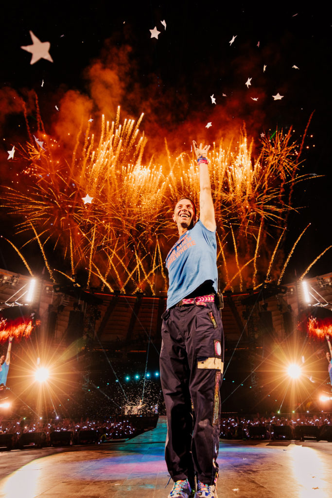 Chris Martin of Coldplay on stage with fireworks