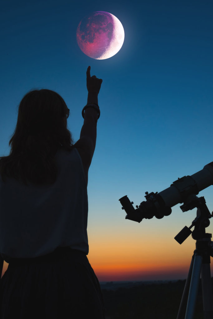 Girl looking at lunar eclipse through a telescope.