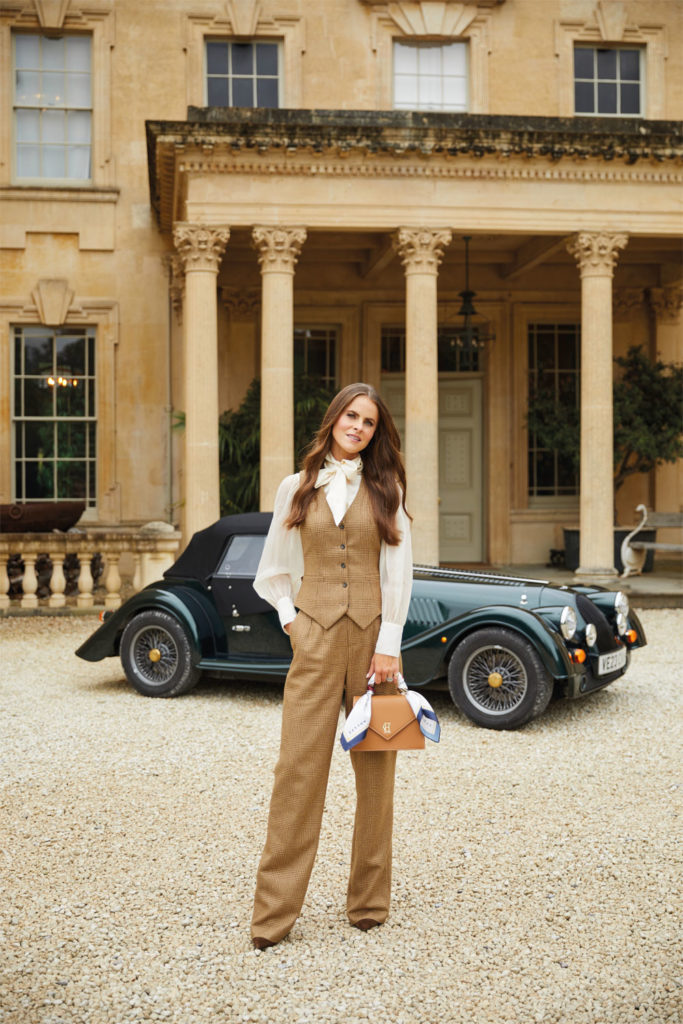 Jade Holland Cooper stood outside a stately home with a vintage car