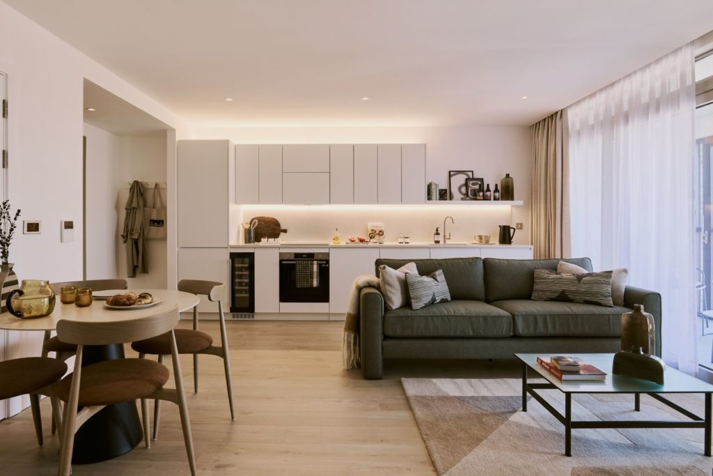 Open plan kitchen living room with gren velvet sofa and white cabinets