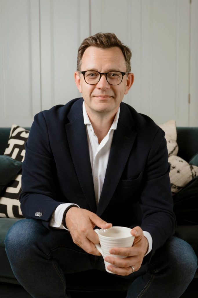 Andy Coulson sitting on a black velvet sofa