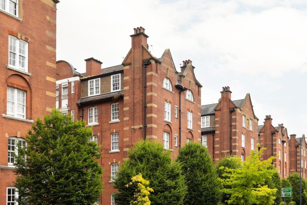 Red brick Chelsea mansion block on tree-lined road