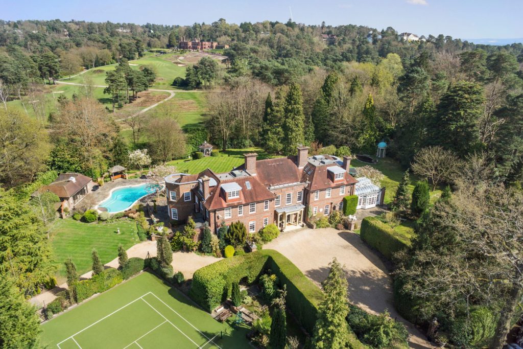 Aerial vie of Surrey home with driveway, outdoor pool and tennis court.