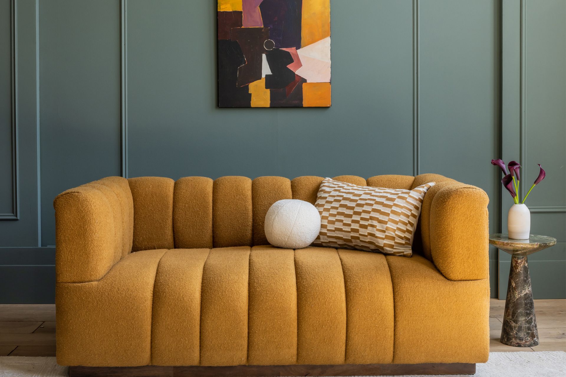 Mustard yellow fluted sofa against a teal panelled wall